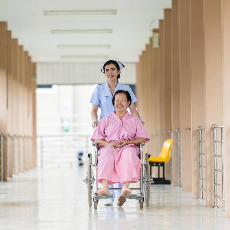 A nursing assistant compassionately assisting an elderly patient with her daily activities in a hospital corridor.