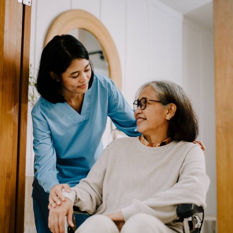 Nurse in blue scrubs attentively attending a patient and assisting her.